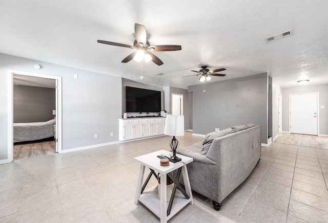 living room featuring ceiling fan, a textured ceiling, and light tile patterned flooring