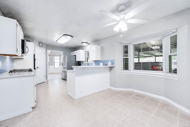 kitchen with ceiling fan, white cabinetry, tasteful backsplash, and stainless steel refrigerator