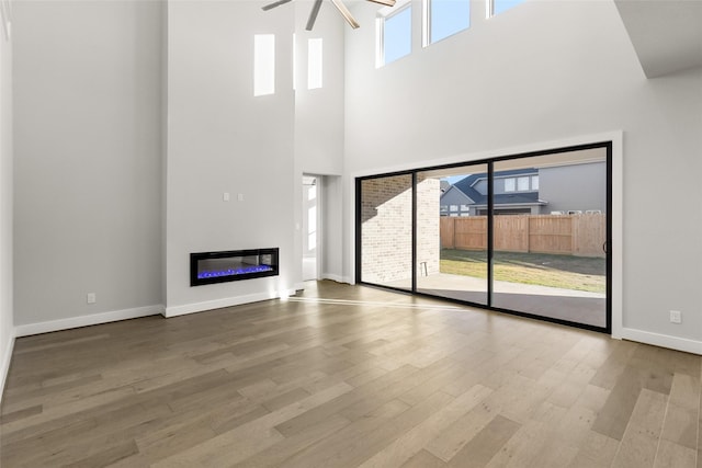 unfurnished living room featuring a high ceiling, hardwood / wood-style floors, and ceiling fan