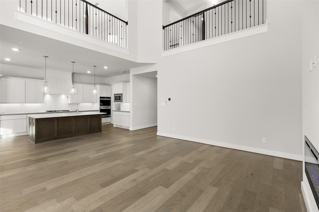 unfurnished living room featuring a towering ceiling and wood-type flooring