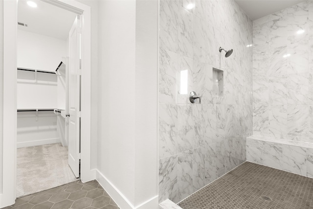 bathroom featuring tile patterned flooring and a tile shower