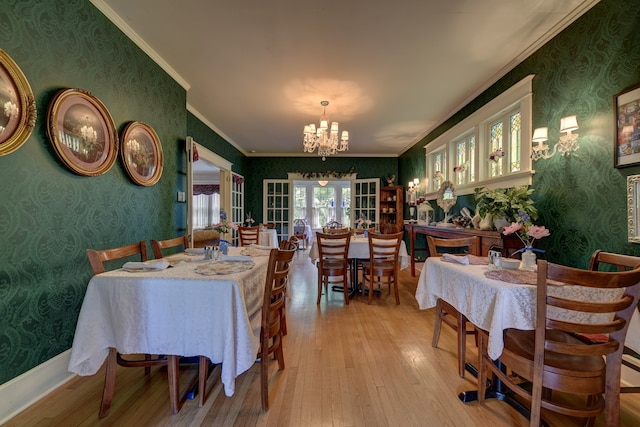 dining space with a notable chandelier, crown molding, french doors, and light hardwood / wood-style flooring