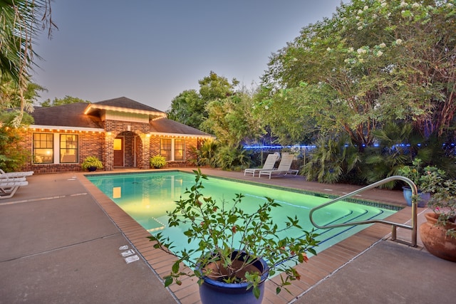 pool at dusk featuring a patio