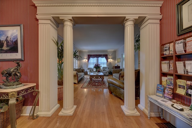 corridor featuring crown molding, decorative columns, and light hardwood / wood-style flooring