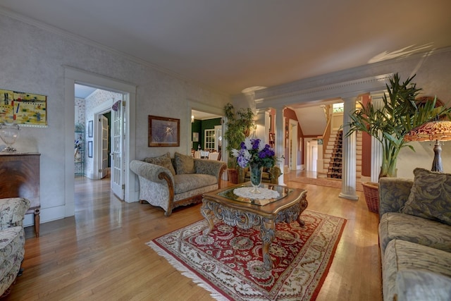 living room featuring crown molding, decorative columns, and light wood-type flooring