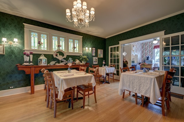 dining area with a chandelier, ornamental molding, and light hardwood / wood-style flooring