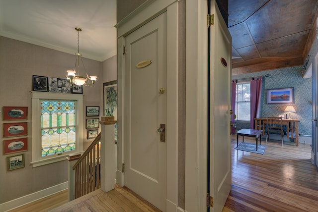 entryway featuring an inviting chandelier, crown molding, a healthy amount of sunlight, and light wood-type flooring