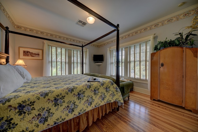 bedroom featuring multiple windows, ornamental molding, and light hardwood / wood-style flooring