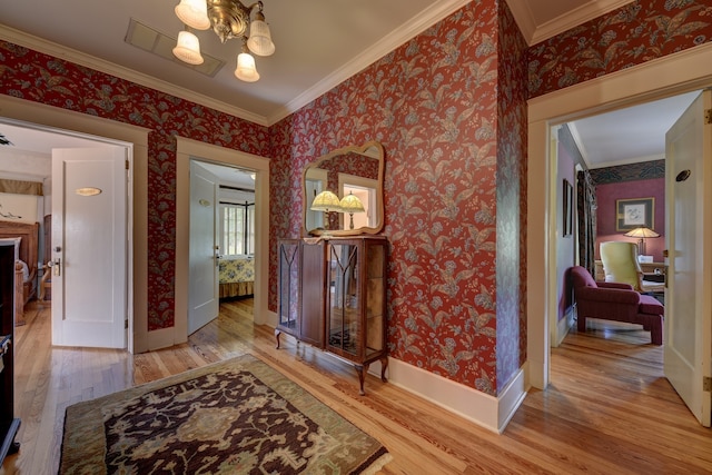 foyer featuring a chandelier, ornamental molding, and light hardwood / wood-style floors