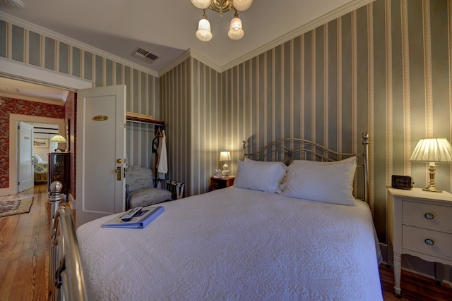 bedroom featuring a closet, ornamental molding, wood-type flooring, and a notable chandelier