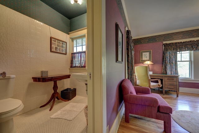 interior space featuring ornamental molding, light wood-type flooring, and tile walls