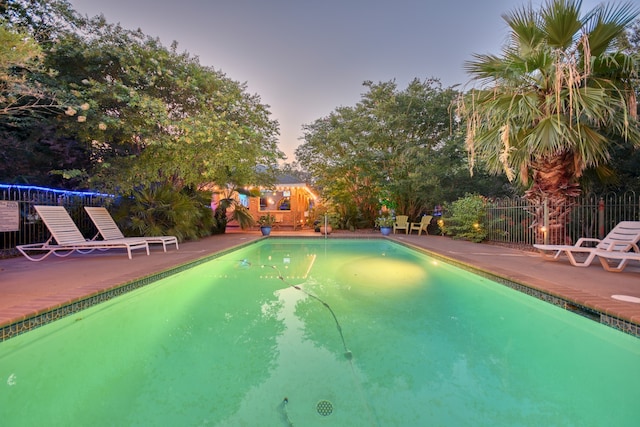 pool at dusk featuring a patio area