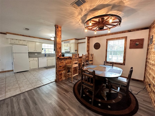 dining area with crown molding, sink, a chandelier, and light tile floors