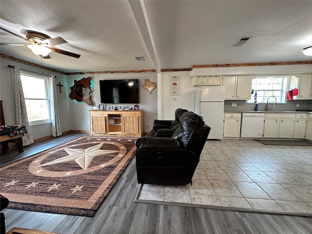 tiled living room with plenty of natural light, ceiling fan, and sink