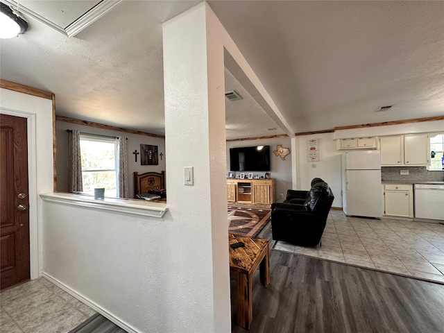 interior space with a textured ceiling, ornamental molding, and light tile floors