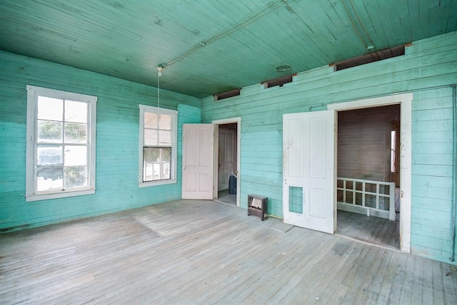 unfurnished room with wood walls, wooden ceiling, and wood-type flooring