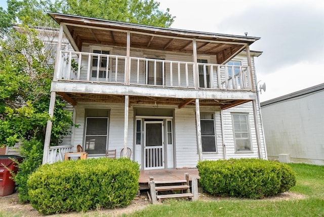 rear view of property featuring covered porch and a balcony