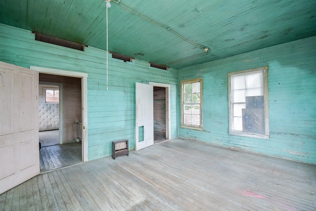 empty room with wooden walls, wood ceiling, and hardwood / wood-style floors