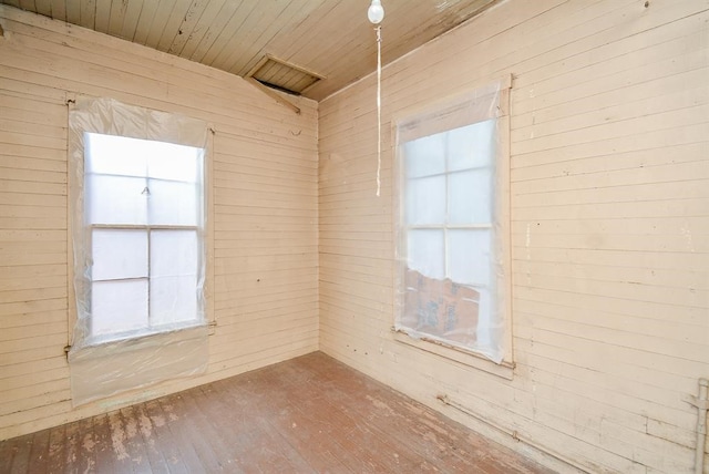 unfurnished room with a healthy amount of sunlight, hardwood / wood-style flooring, and wooden walls