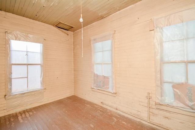 unfurnished room with plenty of natural light, wood ceiling, wooden walls, and hardwood / wood-style flooring