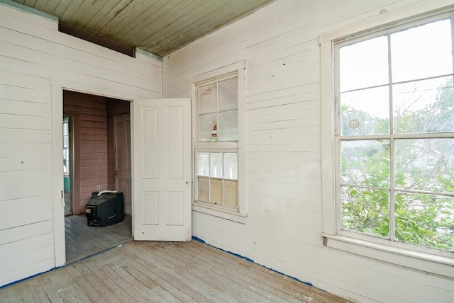 spare room featuring wood ceiling, wood walls, and light hardwood / wood-style floors