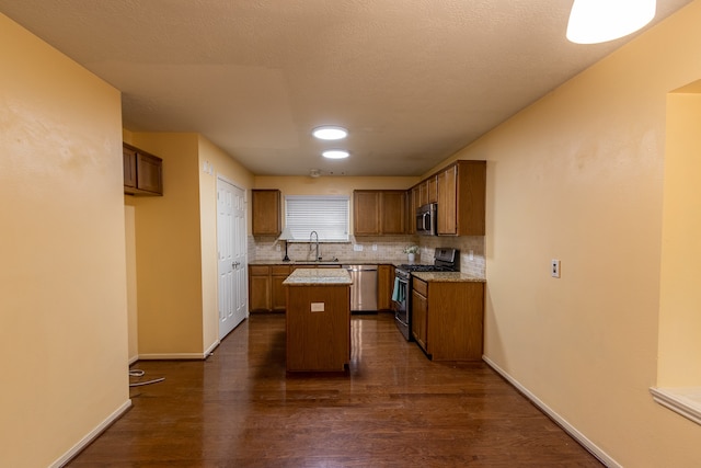 kitchen featuring dark wood-type flooring, backsplash, a kitchen island, stainless steel appliances, and a textured ceiling