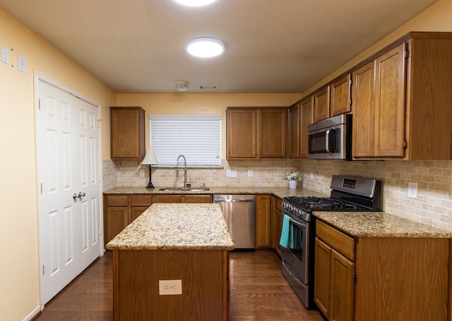 kitchen featuring sink, tasteful backsplash, appliances with stainless steel finishes, a center island, and dark hardwood / wood-style flooring