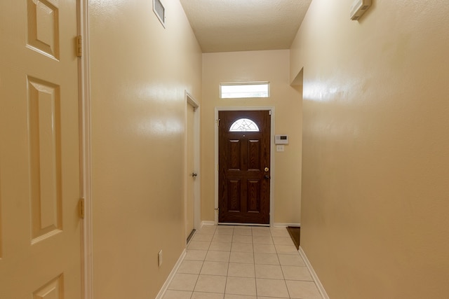 doorway to outside featuring a textured ceiling and light tile patterned floors