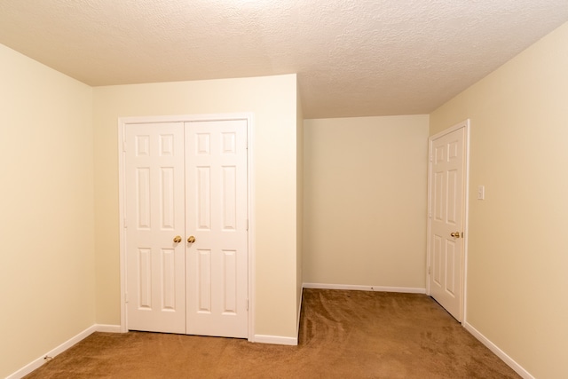 unfurnished bedroom featuring a textured ceiling, a closet, and carpet flooring