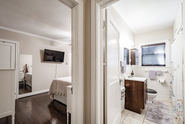 bathroom with toilet, vanity, hardwood / wood-style floors, ornamental molding, and tile walls