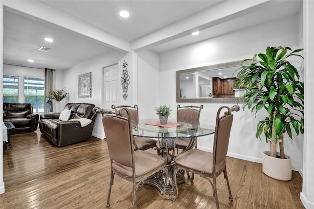 dining space with wood-type flooring and beamed ceiling