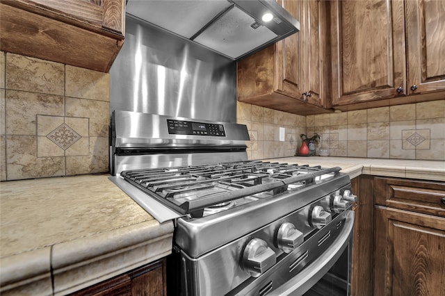 kitchen featuring backsplash, dark brown cabinetry, and stainless steel gas stove