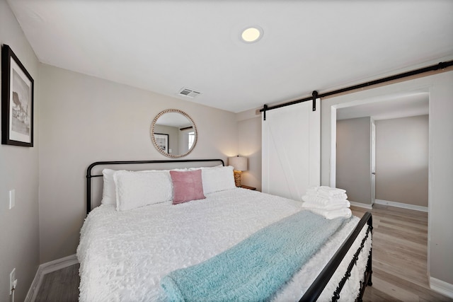 bedroom with a barn door and light hardwood / wood-style flooring