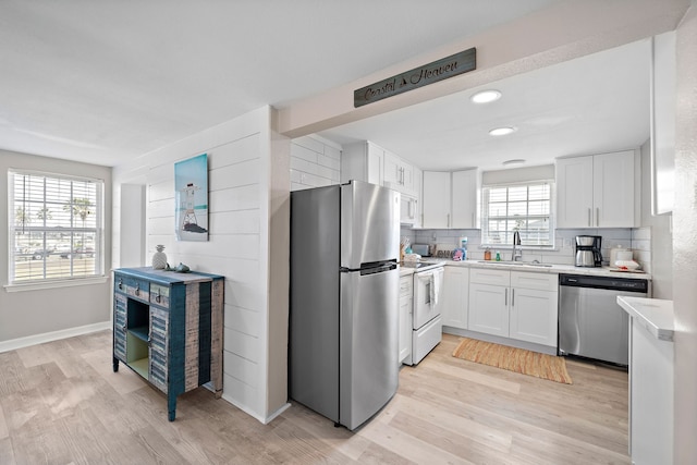 kitchen with light hardwood / wood-style flooring, stainless steel appliances, plenty of natural light, and white cabinets