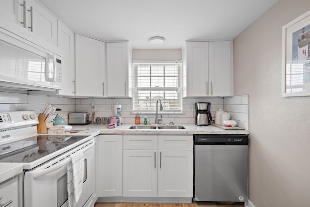 kitchen with white appliances, white cabinetry, backsplash, and sink