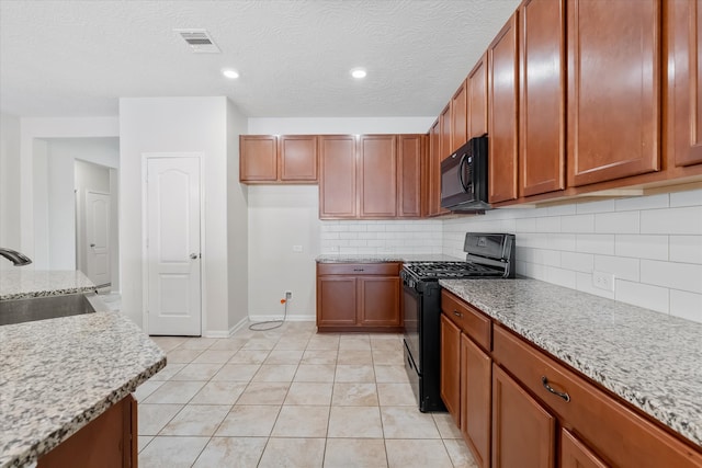 kitchen with sink, tasteful backsplash, light stone counters, a textured ceiling, and black appliances