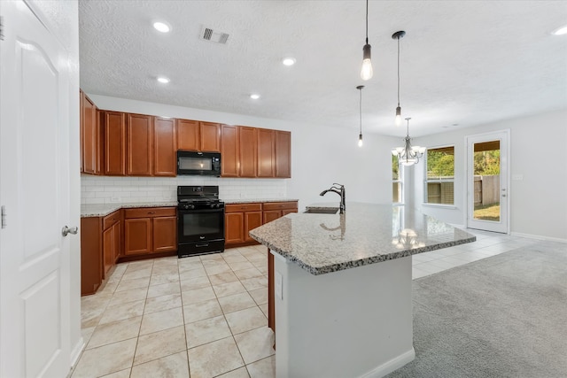 kitchen with light stone countertops, an island with sink, light colored carpet, decorative light fixtures, and black appliances