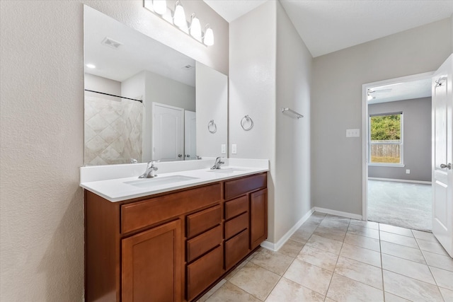 bathroom featuring tile patterned flooring, vanity, ceiling fan, and a tile shower