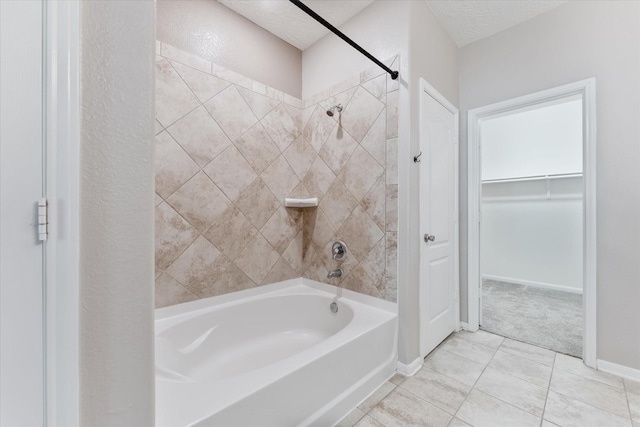 bathroom with tile patterned flooring, tiled shower / bath combo, and a textured ceiling