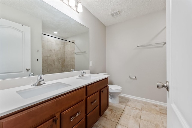 bathroom featuring a tile shower, tile patterned flooring, a textured ceiling, toilet, and vanity