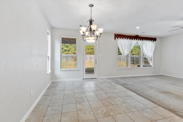 spare room featuring light carpet, a textured ceiling, and ceiling fan with notable chandelier