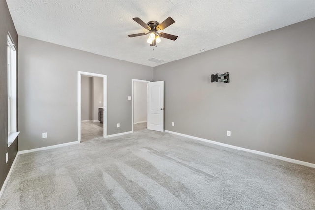 unfurnished bedroom with ceiling fan, light carpet, and a textured ceiling