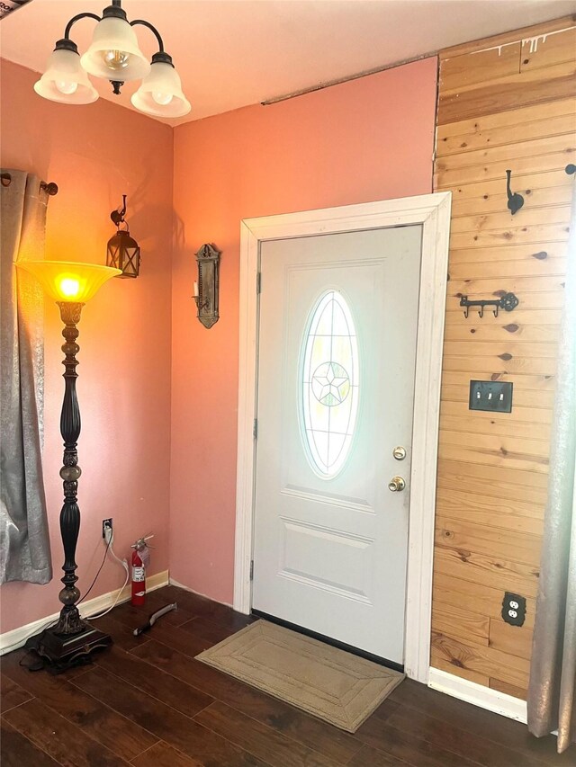 entryway with wooden walls, dark hardwood / wood-style floors, and a chandelier