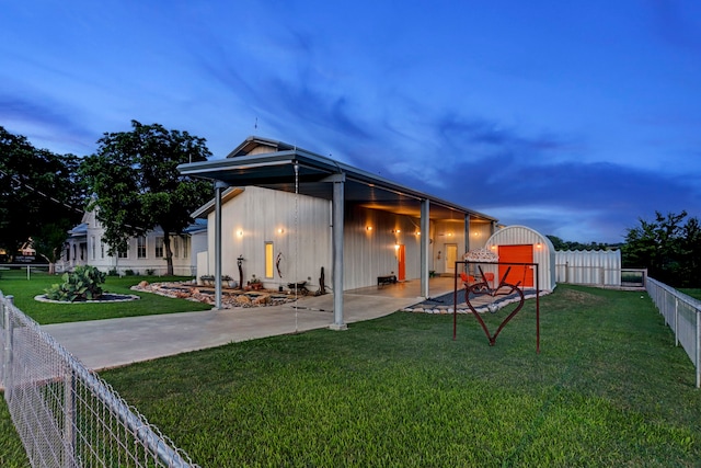 back house at dusk with a lawn and a patio area