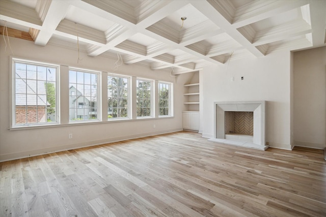 unfurnished living room featuring built in features, baseboards, beam ceiling, and light wood finished floors