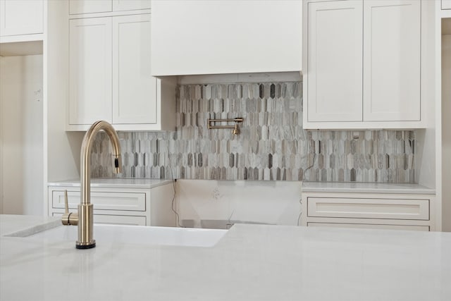 kitchen featuring backsplash, white cabinetry, and sink