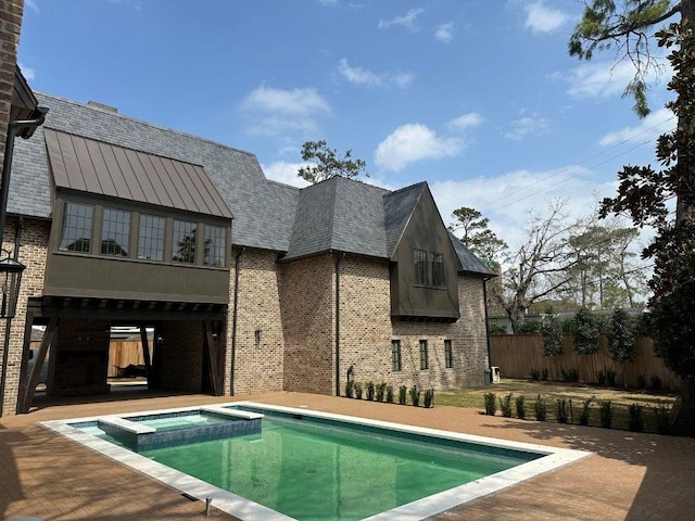 view of pool with a patio, fence, and a pool with connected hot tub