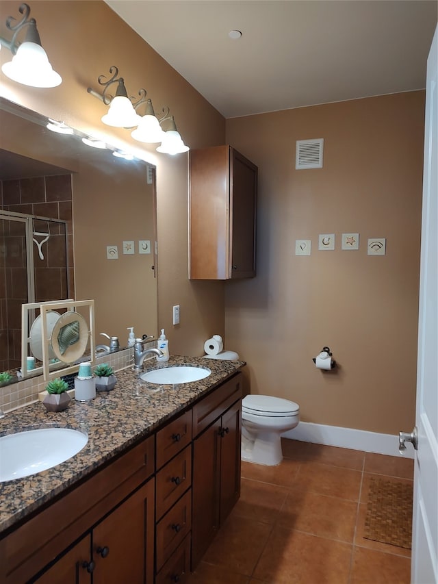 bathroom with tile floors, toilet, and dual bowl vanity