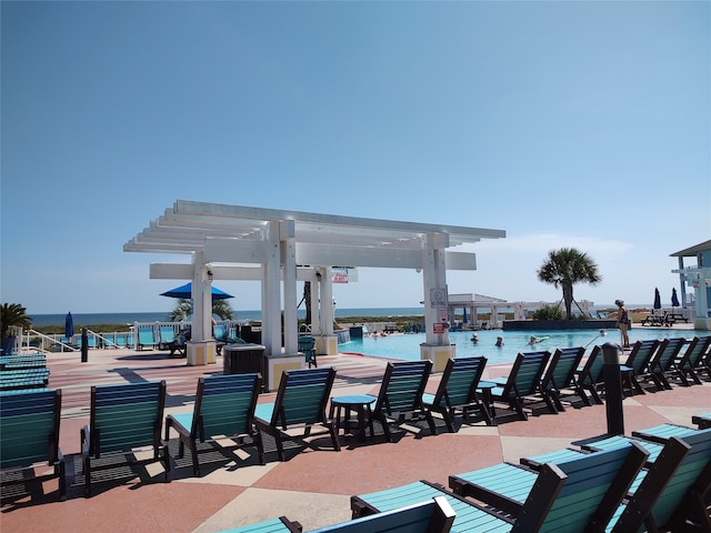 view of patio with a water view, a pergola, and a community pool