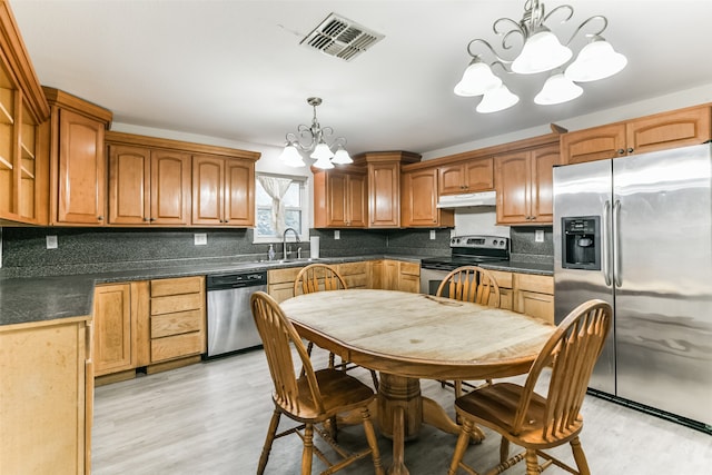 kitchen featuring light hardwood / wood-style floors, tasteful backsplash, appliances with stainless steel finishes, pendant lighting, and a chandelier